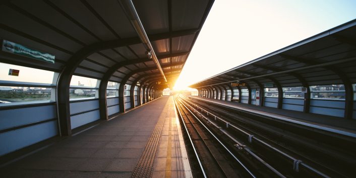 Togspor på et stoppested med solnedgang i bakgrunnen